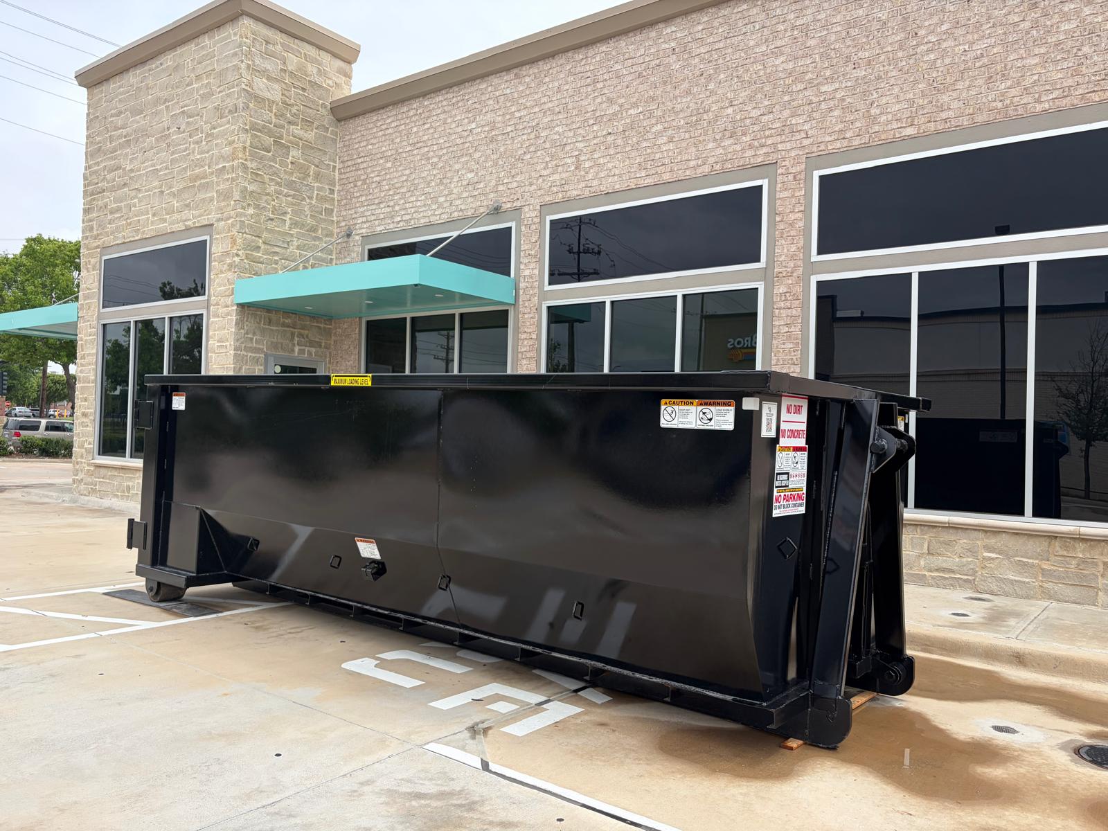 Roll-off dumpster rental delivery in Dallas, TX with skyline in the background