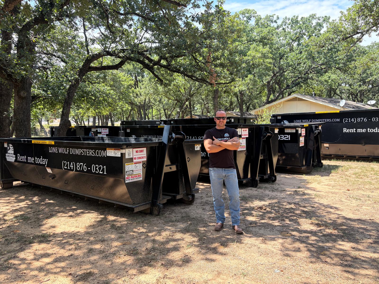 Owner of Lone Wolf Dumpsters standing in front of roll-off dumpster fleet in Dallas-Fort Worth